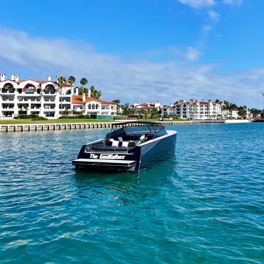 The Godfather Yacht Photos Pics 2014 VanDutch 55 yacht cruising near luxury waterfront residences under a clear blue sky.