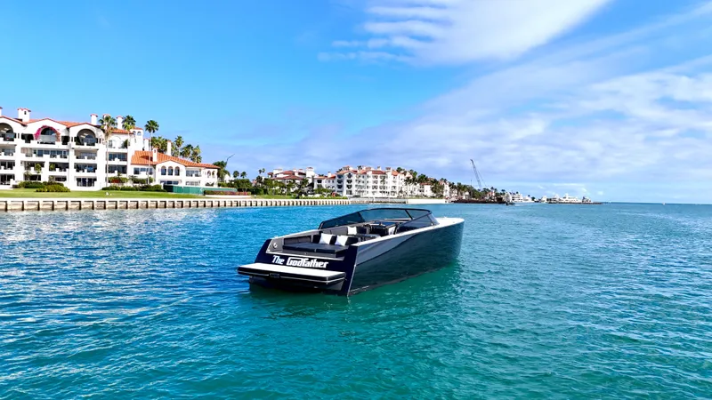 The Godfather Yacht Photos Pics 2014 VanDutch 55 yacht cruising near luxury waterfront homes under a clear blue sky.