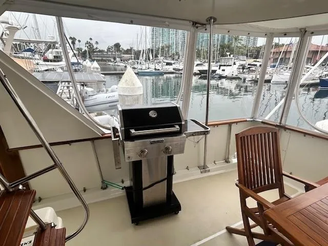 Day Light Yacht Photos Pics 1968 Hatteras 58 CPMY yacht deck with grill and wooden chairs, overlooking marina.