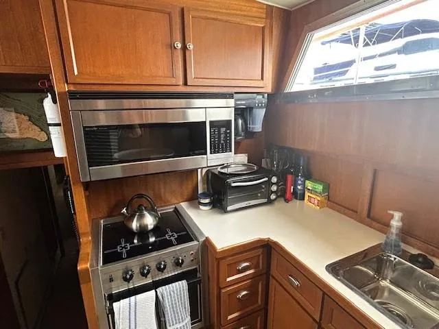 Day Light Yacht Photos Pics 1968 Hatteras 58 CPMY yacht kitchen with wooden cabinets, stainless steel appliances, and countertop essentials.