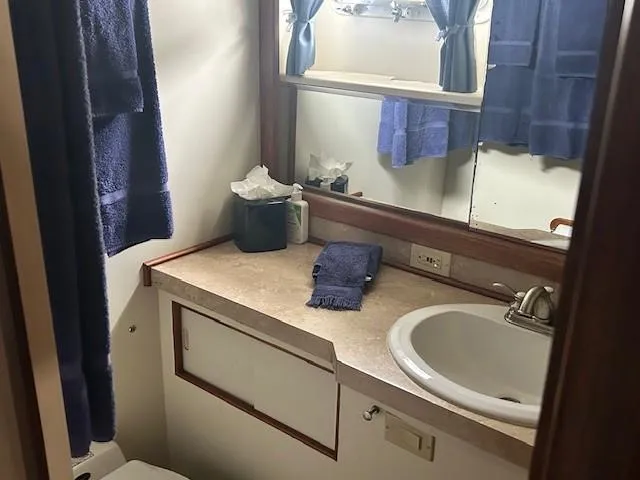 Day Light Yacht Photos Pics Bathroom interior of 1968 Hatteras 58 CPMY yacht with sink, mirror, and blue towels.