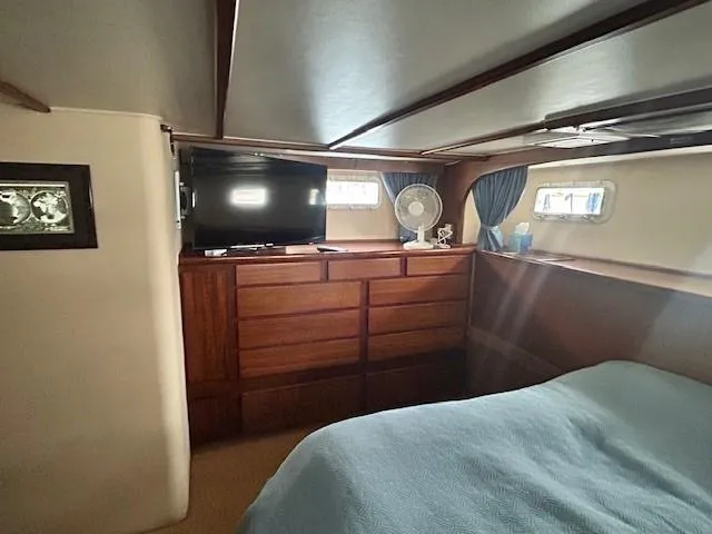 Day Light Yacht Photos Pics 1968 Hatteras 58 CPMY cabin interior with wooden dresser, TV, and bed.