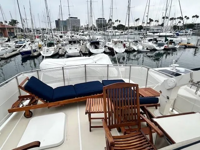 Day Light Yacht Photos Pics 1968 Hatteras 58 CPMY yacht deck with wooden lounge chairs in a marina setting.