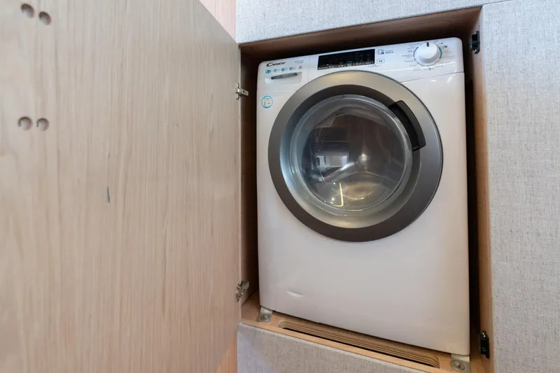  Yacht Photos Pics Washing machine inside Beneteau Monte Carlo 52 yacht, 2022 model, in a wooden cabinet.