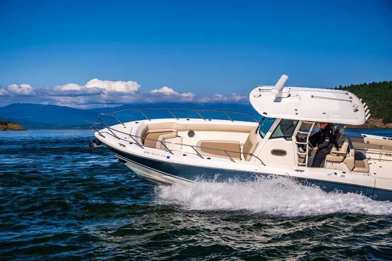  Yacht Photos Pics 2017 Boston Whaler 330 Outrage cruising on open water under clear blue skies.