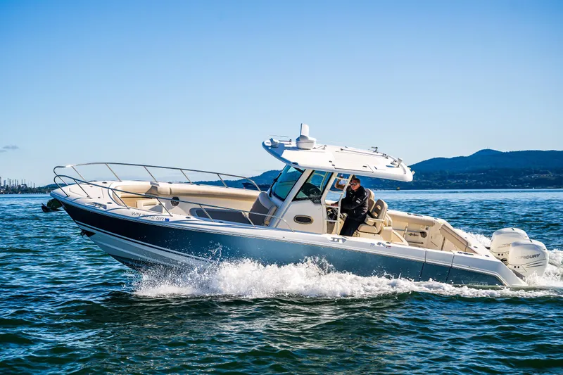  Yacht Photos Pics 2017 Boston Whaler 330 Outrage cruising on open water under clear blue skies.