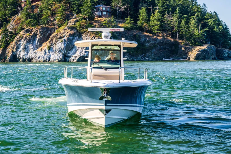  Yacht Photos Pics 2017 Boston Whaler 330 Outrage cruising on scenic waters near rocky shoreline.