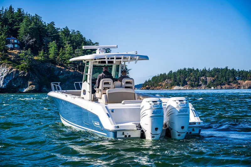  Yacht Photos Pics 2017 Boston Whaler 330 Outrage boat cruising on scenic waters near forested coastline.