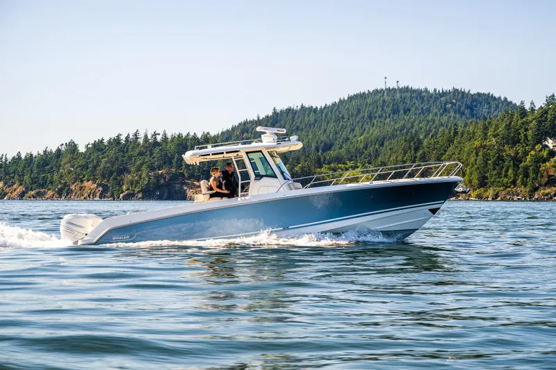  Yacht Photos Pics 2017 Boston Whaler 330 Outrage cruising on scenic water with forested hills in the background.