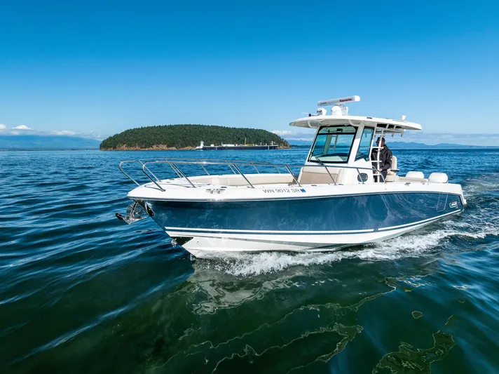  Yacht Photos Pics 2017 Boston Whaler 330 Outrage cruising on open water under clear blue skies.