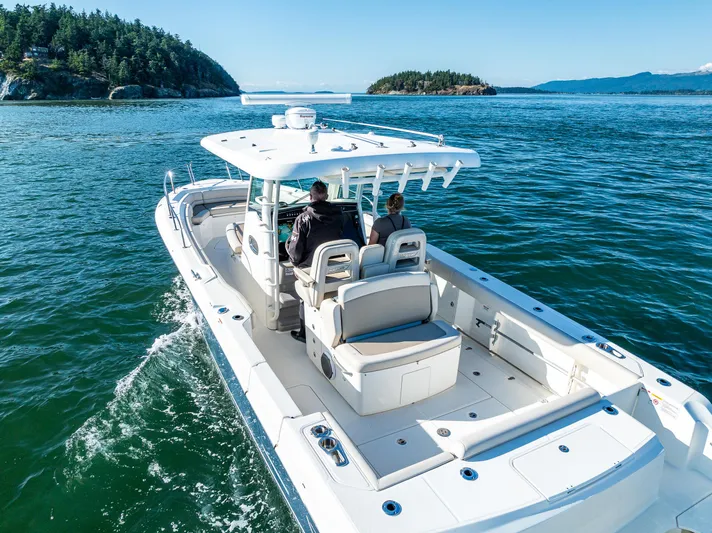 Yacht Photos Pics 2017 Boston Whaler 330 Outrage cruising on scenic waters near forested islands.