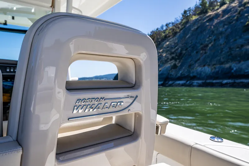  Yacht Photos Pics Boston Whaler 330 Outrage 2017 boat seat with scenic water and cliff background.