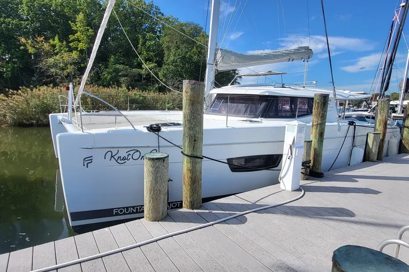 Knot On Call Yacht Photos Pics 2018 Fountaine Pajot Helia 44 catamaran docked at marina, surrounded by lush greenery.