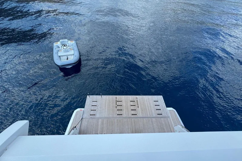  Yacht Photos Pics 2024 Azimut 60 yacht with wooden deck and small boat on calm water.