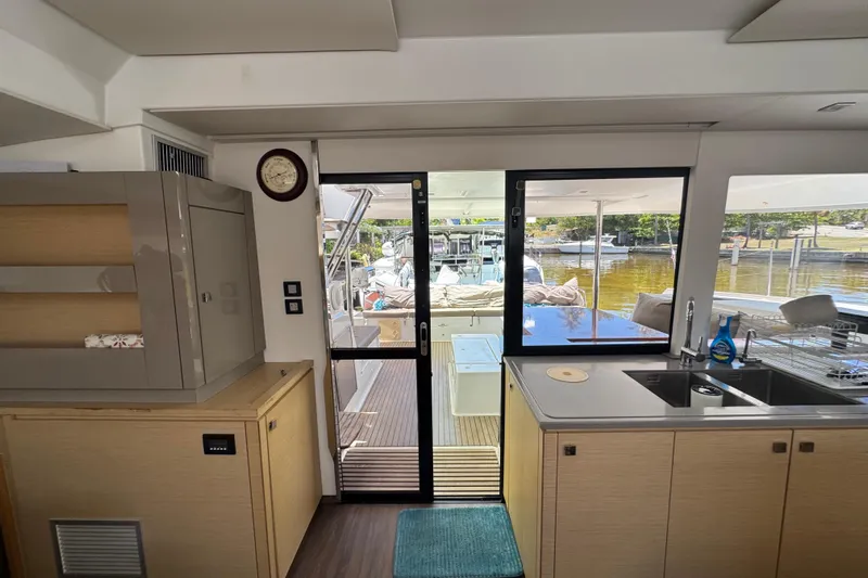 Ten:10 Yacht Photos Pics Interior view of 2017 Fountaine Pajot SABA 50 catamaran, featuring kitchen and outdoor deck access.