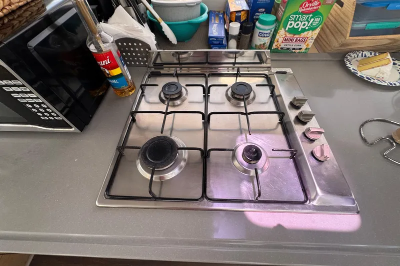 Ten:10 Yacht Photos Pics Stainless steel stove on Fountaine Pajot SABA 50 yacht, surrounded by kitchen items.