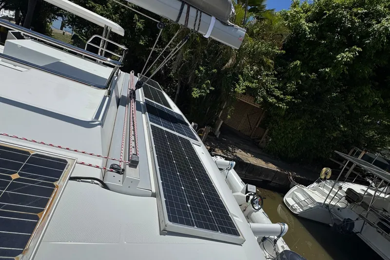 Ten:10 Yacht Photos Pics 2017 Fountaine Pajot SABA 50 catamaran with solar panels on deck, docked near lush greenery.