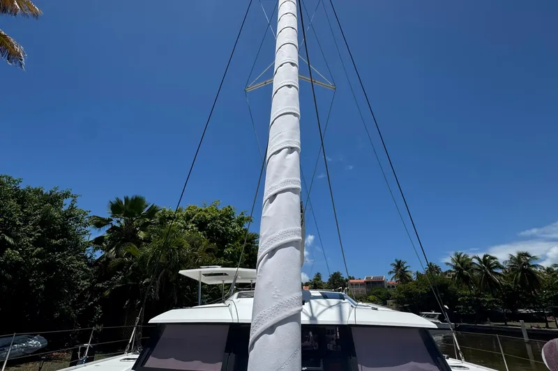 Ten:10 Yacht Photos Pics 2017 Fountaine Pajot SABA 50 catamaran mast against clear blue sky and lush greenery.
