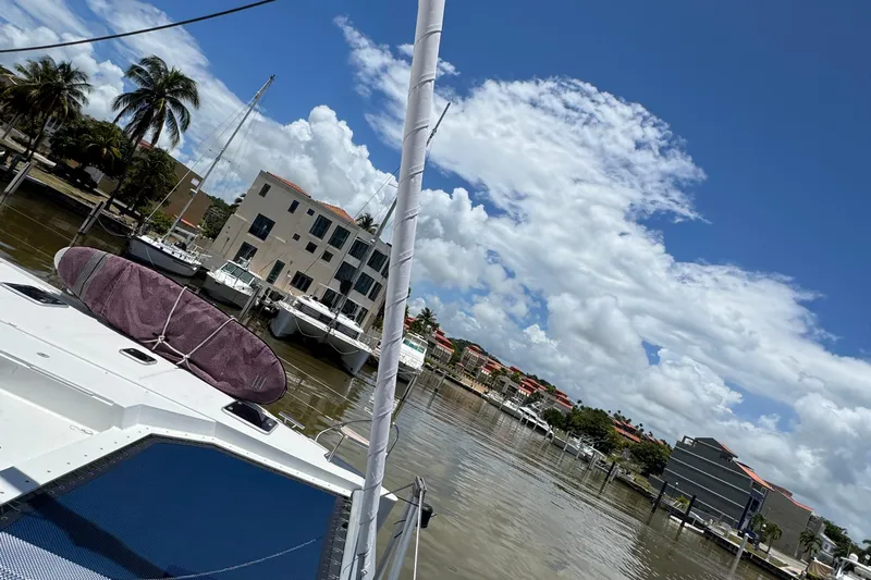 Ten:10 Yacht Photos Pics 2017 Fountaine Pajot SABA 50 catamaran docked in a sunny marina with palm trees.