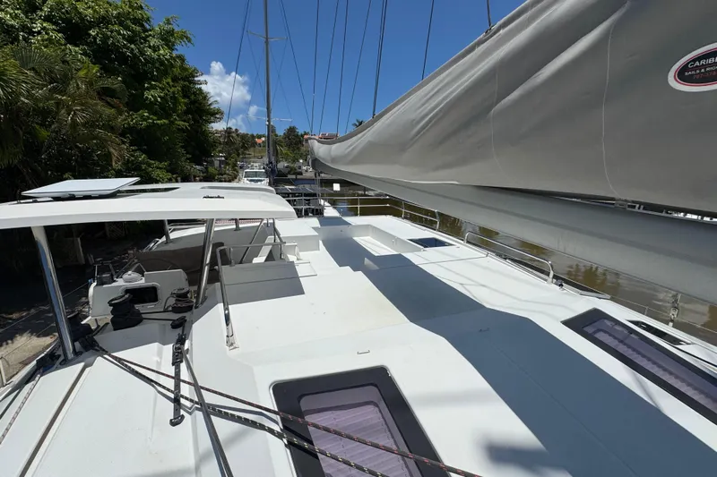 Ten:10 Yacht Photos Pics 2017 Fountaine Pajot SABA 50 catamaran deck with sails, docked near lush greenery.