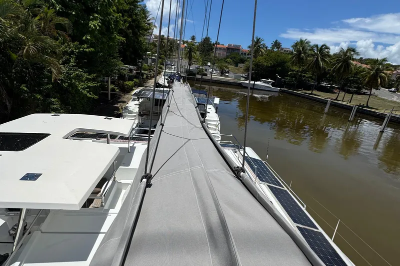 Ten:10 Yacht Photos Pics 2017 Fountaine Pajot SABA 50 catamaran docked by a lush, tropical shoreline.
