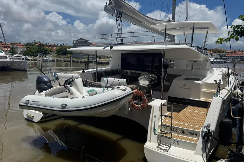 Ten:10 Yacht Photos Pics 2017 Fountaine Pajot SABA 50 catamaran docked with inflatable boat, sunny marina setting.