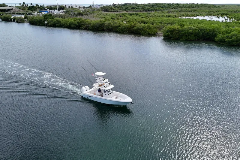  Yacht Photos Pics 2018 Everglades 335 Center Console boat cruising on a serene waterway near lush greenery.