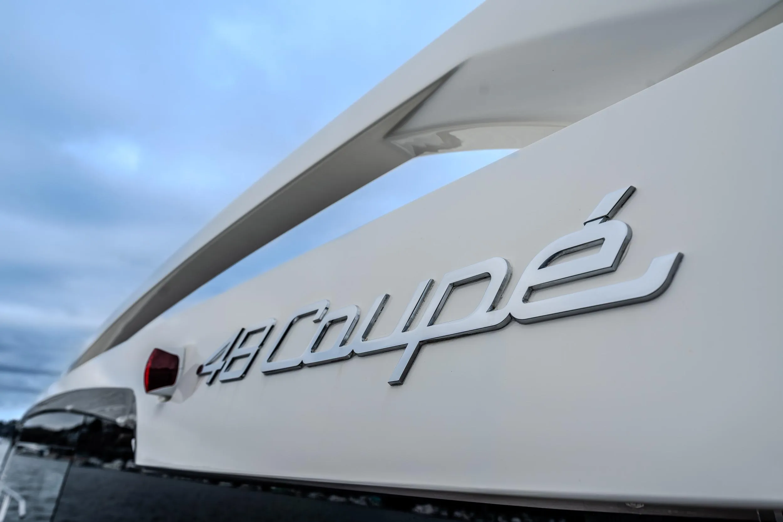 2026 Absolute 48 Coupe yacht logo against a cloudy sky backdrop.