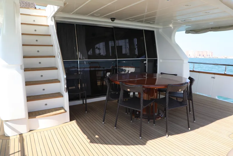 Yacht Photos Pics Outdoor dining area on 2005 Falcon 90 yacht with wooden deck and staircase.