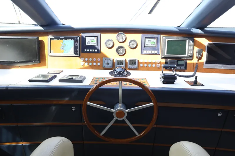  Yacht Photos Pics Control panel of a 2005 Falcon 90 yacht with navigation instruments and steering wheel.