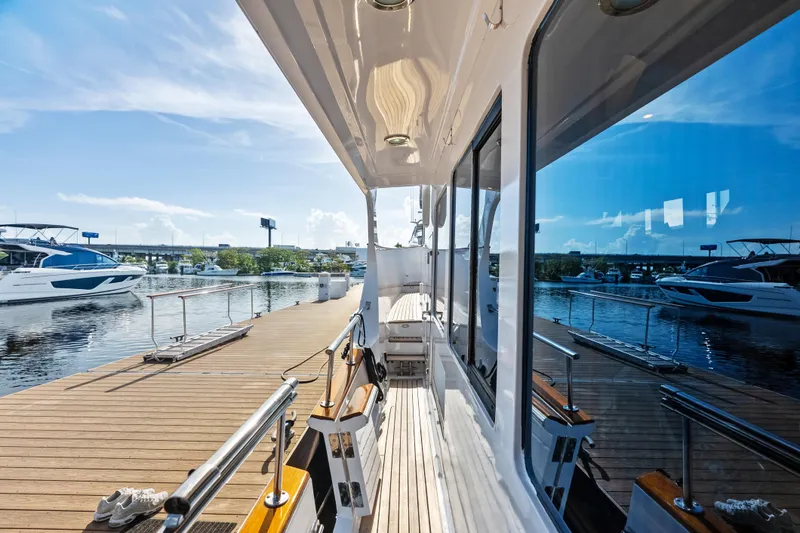 El Legado Yacht Photos Pics 2005 Grand Banks 72 Aleutian RP yacht docked, reflecting water and sky, with nearby boats.