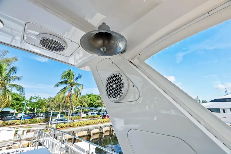 El Legado Yacht Photos Pics 2005 Grand Banks 72 Aleutian RP yacht detail with bell and speakers, docked near palm trees.
