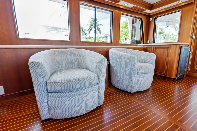 El Legado Yacht Photos Pics Luxurious interior of 2005 Grand Banks 72 Aleutian RP with patterned chairs and wooden flooring.
