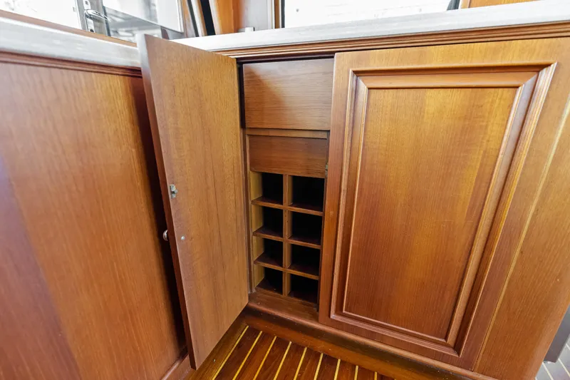 El Legado Yacht Photos Pics Wooden cabinet with open door revealing storage shelves on 2005 Grand Banks 72 Aleutian RP yacht.