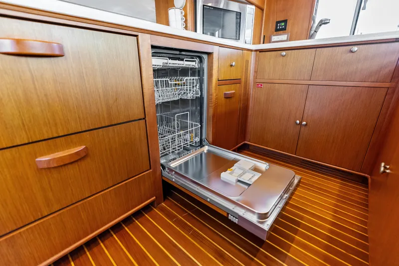 El Legado Yacht Photos Pics Open dishwasher in the wooden kitchen of a 2005 Grand Banks 72 Aleutian RP yacht.