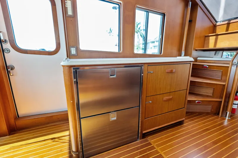 El Legado Yacht Photos Pics Interior of 2005 Grand Banks 72 Aleutian RP yacht with wooden cabinetry and stainless steel fridge.
