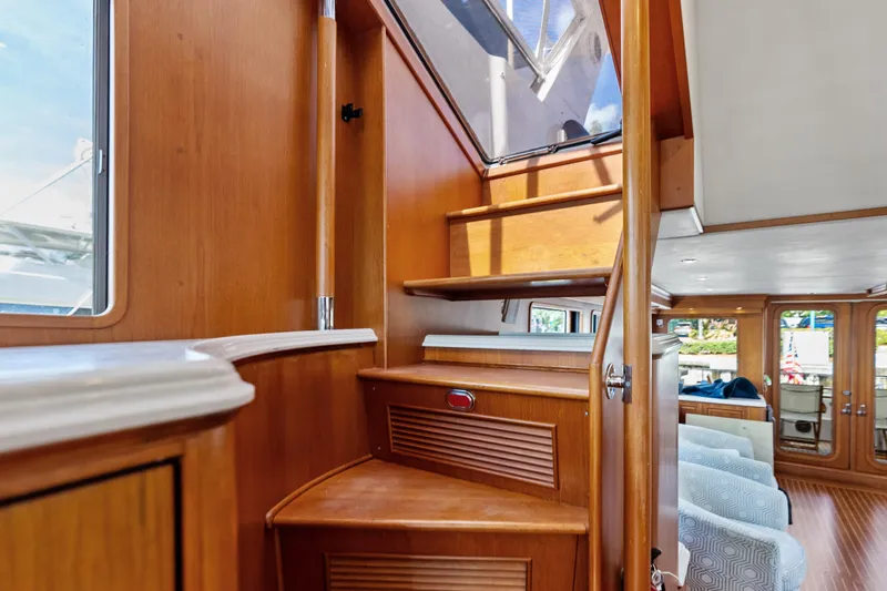 El Legado Yacht Photos Pics Interior view of 2005 Grand Banks 72 Aleutian RP yacht with wooden stairs and seating area.