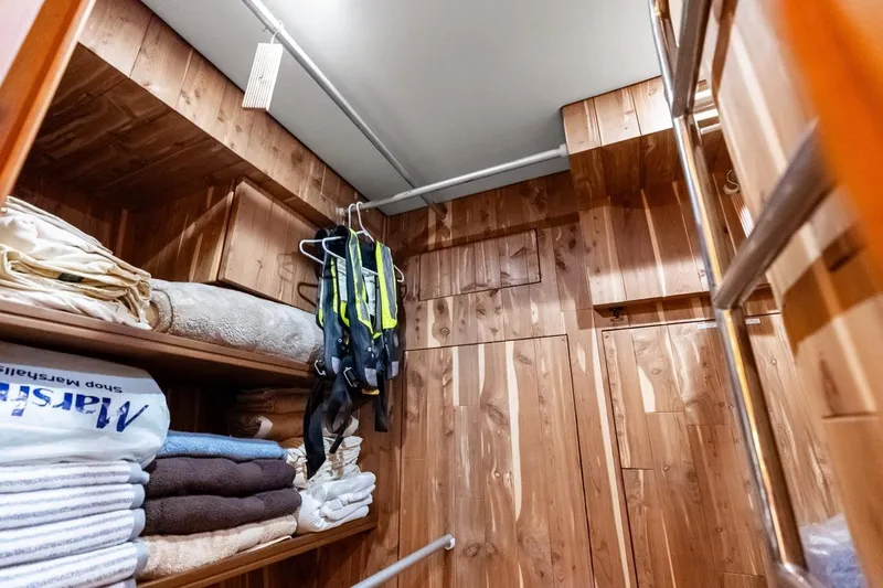 El Legado Yacht Photos Pics Wood-paneled storage room on 2005 Grand Banks 72 Aleutian RP yacht with shelves and hanging gear.