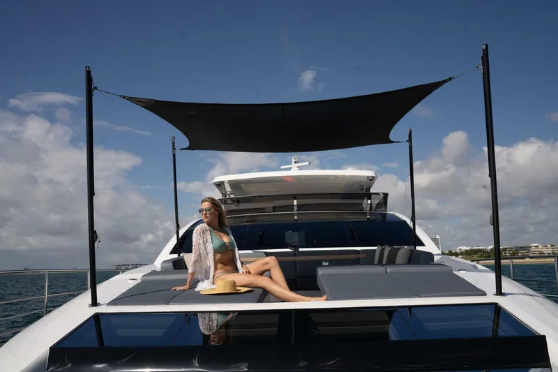  Yacht Photos Pics Luxury Pearl 95 yacht, 2020 model, with a person relaxing on deck under a sunshade.