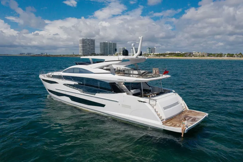  Yacht Photos Pics Luxurious 2020 Pearl 95 yacht cruising on the ocean near a coastal cityscape.