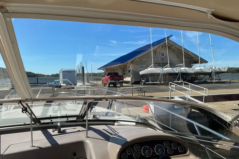 Knee Deep Yacht Photos Pics 2003 Regal Commodore 4260 yacht docked at marina with sailboats and boathouse in view.