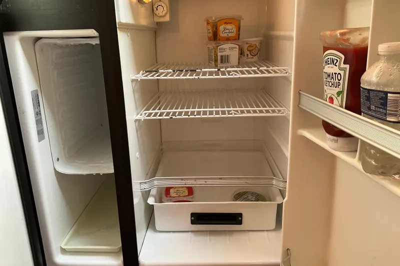 Knee Deep Yacht Photos Pics Open refrigerator with condiments and minimal food items, inside a 2003 Regal Commodore 4260.