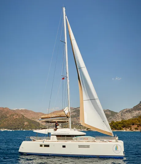  Yacht Photos Pics 2014 Lagoon 52 F catamaran sailing on blue waters with scenic mountain backdrop.