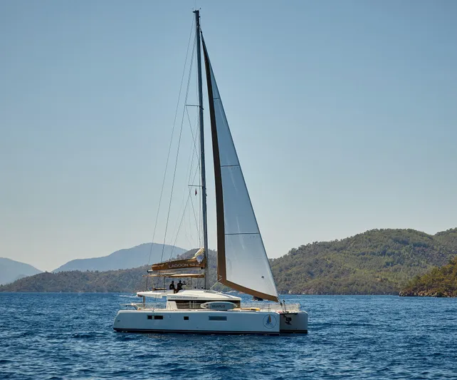  Yacht Photos Pics 2014 Lagoon 52 F catamaran sailing on a serene blue sea with distant hills.