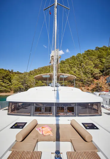  Yacht Photos Pics 2014 Lagoon 52 F catamaran with sunbathing area, anchored near lush green shoreline.