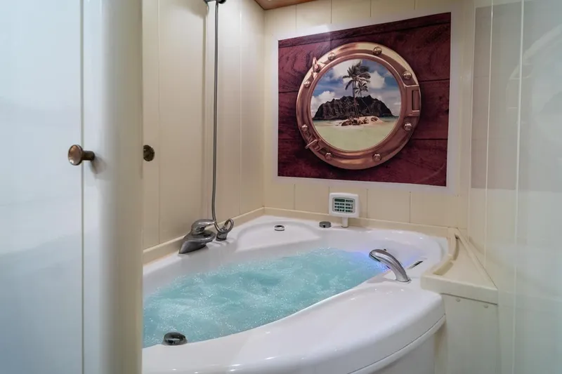  Yacht Photos Pics Luxurious bathroom with jacuzzi on 1999 Ferretti Customline 94 yacht, featuring tropical decor.