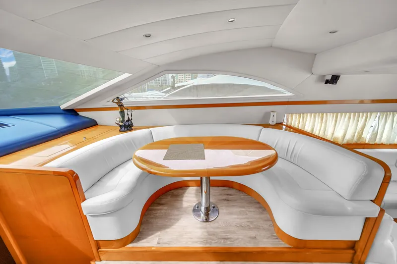  Yacht Photos Pics 2006 Uniesse 58 yacht interior with curved white seating and wooden table.
