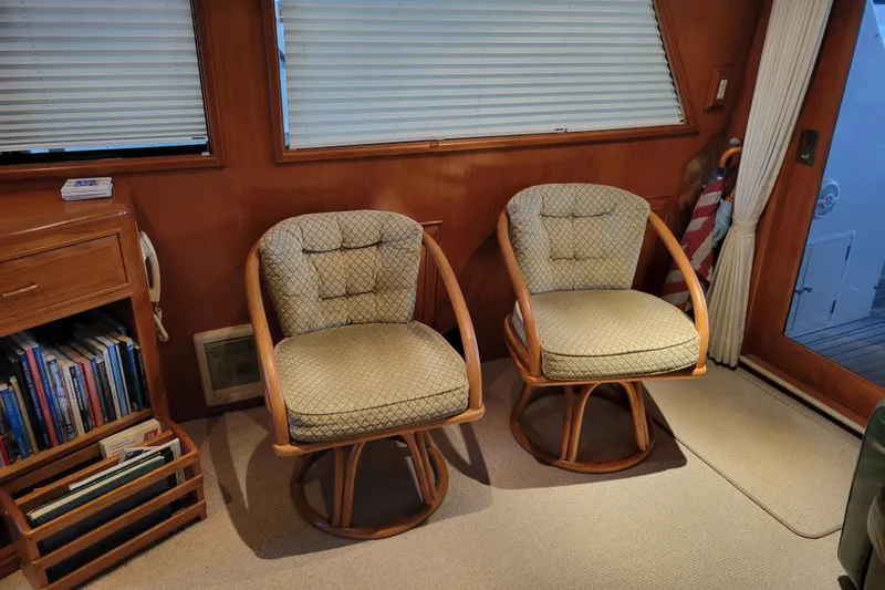 Sumptin Special Yacht Photos Pics Interior of 1990 Ocean Alexander 520 Pilothouse with two cushioned chairs and bookshelf.
