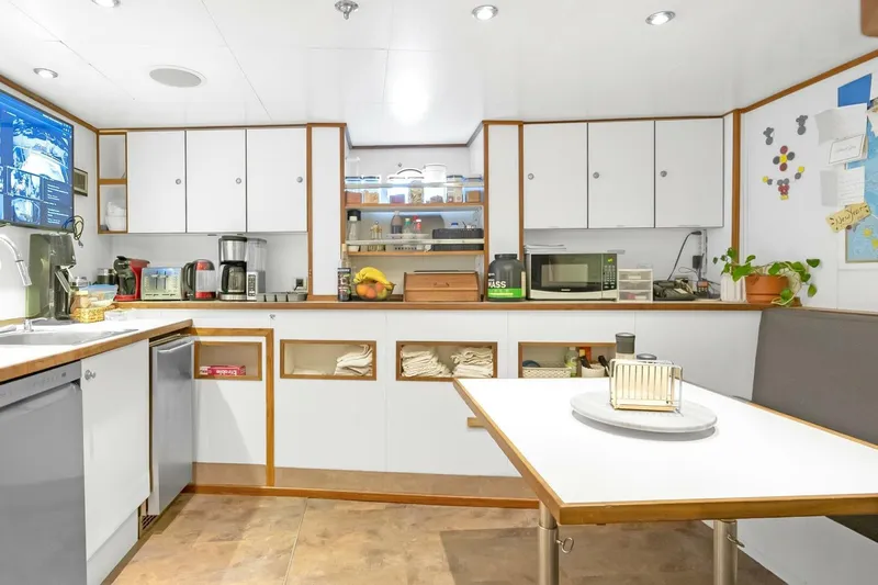 Unforgettable Yacht Photos Pics Modern yacht kitchen with white cabinets, appliances, and dining area, Royal Denship M.Y. 2003.