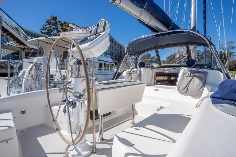 Aries Yacht Photos Pics 2002 Catalina 380 sailboat cockpit with steering wheel, docked at marina under clear blue sky.